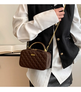 Detail of classic brown quilted PU leather box bag with gold handle and chain strap