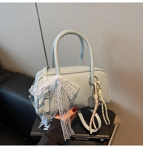 Detail of light blue leather pillow bag featuring white lace scarf and tennis racket charm