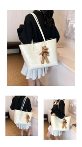 Dettaglio della borsa tote in pelle PU bianca con trama screpolata e orsetto