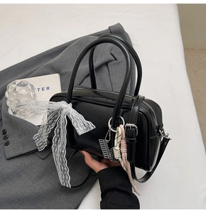 Detail of black Boston pillow bag featuring side lace bow and silver 'W' letter charm