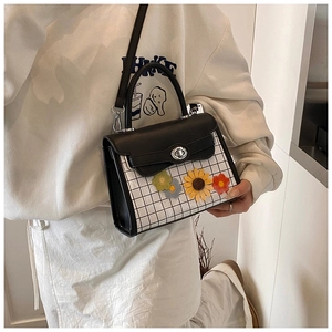 Detail shot of black and white checkered crossbody bag with 3D sunflower floral accents
