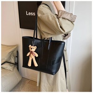 Dettaglio della borsa tote nera patchwork con trama a pietra e ciondolo a forma di orso