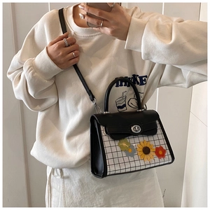 Detail showing checkered crossbody bag with sunflower charms and silver twist lock closure