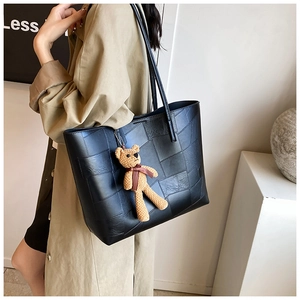 Dettaglio della borsa tote nera in patchwork di pelle con ciondolo a forma di orsetto