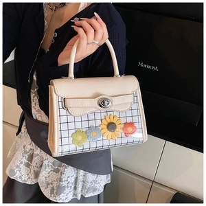 Detail of cream white handbag featuring transparent black grid and knit flower charms