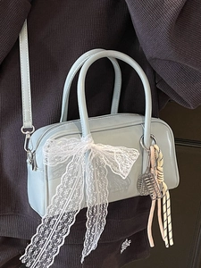 Blue patent leather boston bag with lace bow and tennis racket charm worn on shoulder