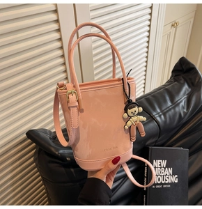 Détail du sac seau rose brillant avec ferrures dorées et pendentif de poupée de dessin