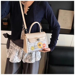 Detail view of beige square crossbody bag featuring floral motifs and checkered fabric texture