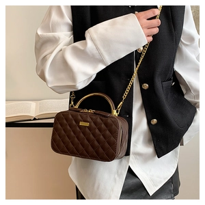 Deep brown quilted crossbody bag with golden handle and chain strap on a stylish model