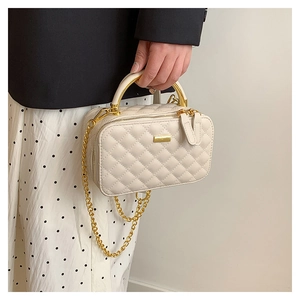 Classic white quilted crossbody bag with gold metal handle and chain strap on a model