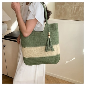 Detail of green and beige striped woven tote bag with fringe tassels and wooden beads