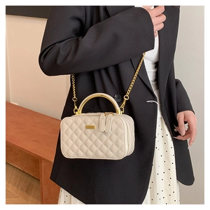 Close-up of quilted cream crossbody bag with gold handle on elegant outfit model