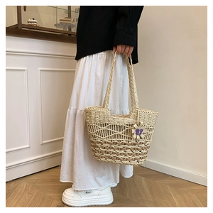 Detail view of handmade straw tote bag with grid texture and purple flower charm