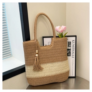 Detail of hand-woven tote bag showing striped texture and bohemian tassel with wooden beads