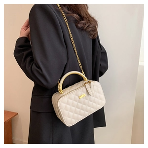 Detail of beige quilted crossbody bag with golden handle and fine chain strap on model