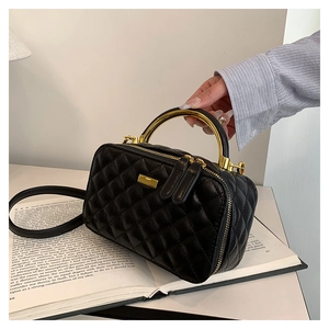 Detail view of the black quilted PU leather bag with elegant gold circular metal handle