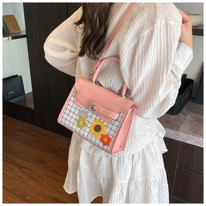 Detail of pink plaid handbag featuring handmade 3D crochet flowers and metal buckle