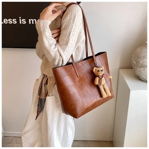 Vista dettagliata della borsa tote in pelle marrone con texture patchwork e ciondolo