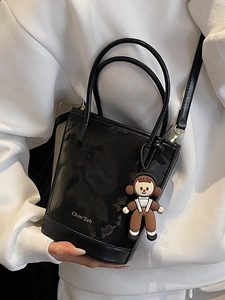 Sac seau noir brillant avec inscription dorée et breloque poupée pour le quotidien