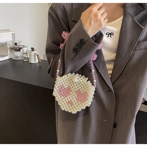 Detail of handmade pearl beaded mini bag with pink heart patterns and chain strap