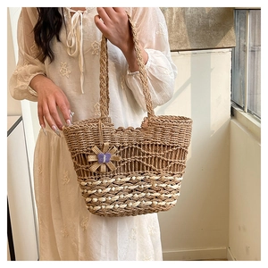 Detailed texture of handmade straw woven tote bag with cream stripes and flower charm