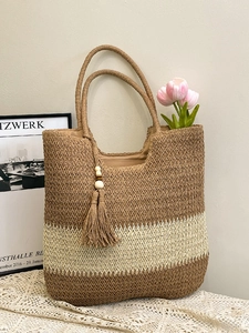 Handwoven straw tote bag with brown and cream stripes and decorative tassel pendant
