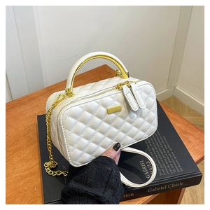 Detail view of a white quilted PU leather box bag with gold metal handle and chain strap