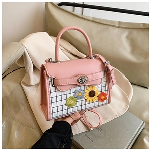 Close-up of pink leather handbag featuring floral embroidery and silver metal twist lock