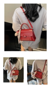 Détail d'un sac à bandoulière en cuir rouge avec rabat et pendentif en peluche