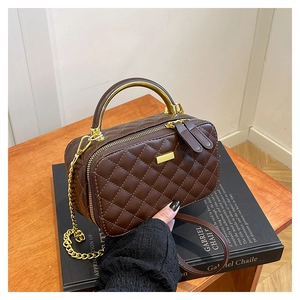 Detailed view of brown quilted crossbody bag with gold metal handle and chain strap