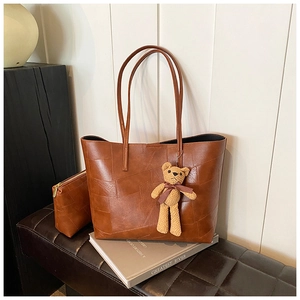 Dettaglio della borsa tote patchwork marrone con pochette a zip e ciondolo a forma di orso
