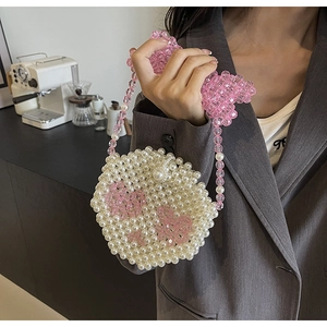 Close-up of handmade round pearl bag with pink bead pattern on a stylish crossbody strap