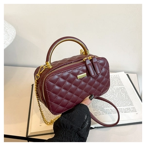 Detailed view of wine red quilted PU leather bag with golden semicircular metal handle