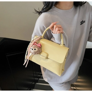Détail du mini sac en cuir jaune clair avec breloque ours et cordon sur la poignée