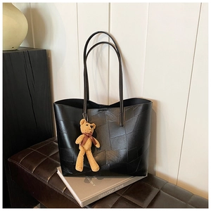 Dettaglio di una borsa tote nera patchwork con un grazioso ciondolo a forma di orsetto