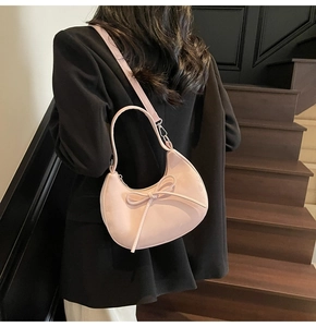 Vue arrière d'un mannequin portant un sac hobo rose avec nœud sur un blazer noir