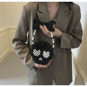 Detail of handmade beaded skull mini bag featuring a black bow handle and pearl chain