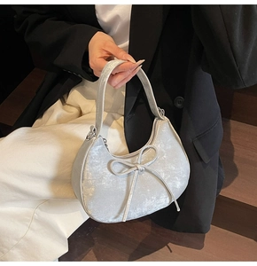 Détail du sac à main croissant argenté avec nœud en soie et finition métallique