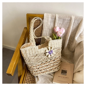 Detail of handmade straw tote bag featuring hollow-out diamond weave and floral charm