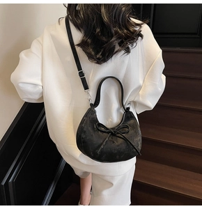 Sac croissant noir avec détail nœud porté en bandoulière par un mannequin