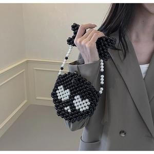 Detail of handcrafted mini beaded crossbody bag with white skull pattern and chain strap