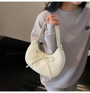 Détail d'un sac demi-lune crème avec un nœud élégant et une texture en similicuir lisse