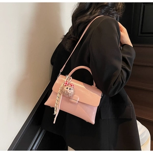 Gros plan du sac bandoulière rose brillant avec breloque peluche et ruban sur modèle