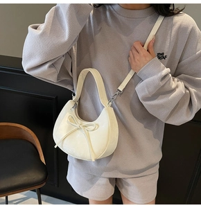 Vue détaillée du nœud décoratif et de la texture en cuir lisse du sac en forme de croissant