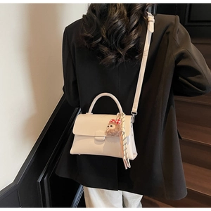 Détail du petit sac blanc rectangulaire avec charm en peluche et foulard en soie rayé