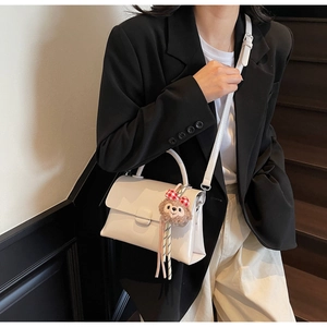 Détail du sac à bandoulière minimaliste blanc cassé en similicuir avec charm peluche