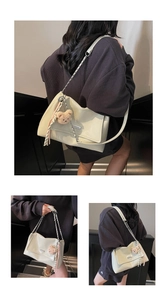 Detail of soft cream tote bag with silver chain strap and cute bear charm accent