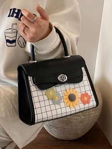 Chic black leather handbag with plaid pattern and vibrant knitted flower accents