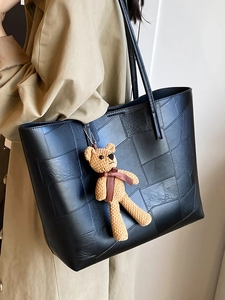Borsa tote nera patchwork con ciondolo a forma di orso e modella in trench kaki