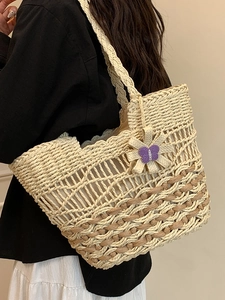 Handwoven straw tote bag with floral accents and purple charm for beach vacation